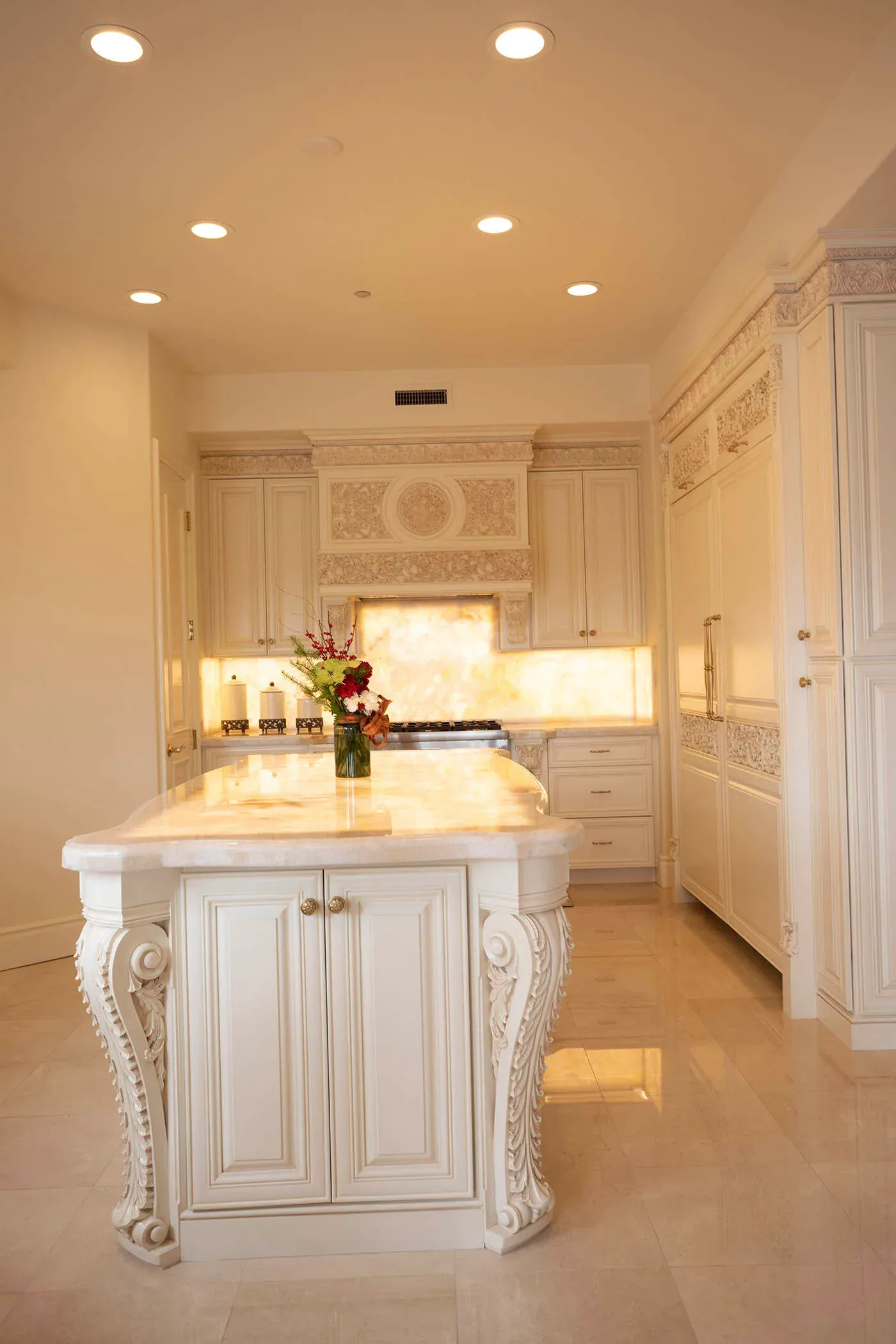 Backlit onyx island with carved corbels in a cream kitchen