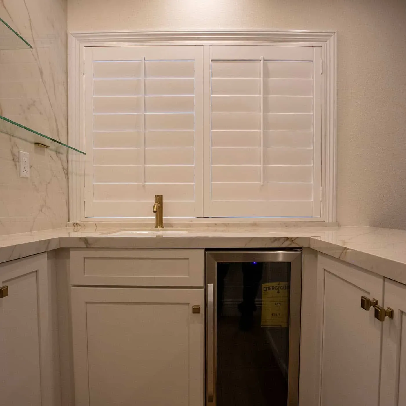 Bar with a brass tap, glass shelves and a shuttered window