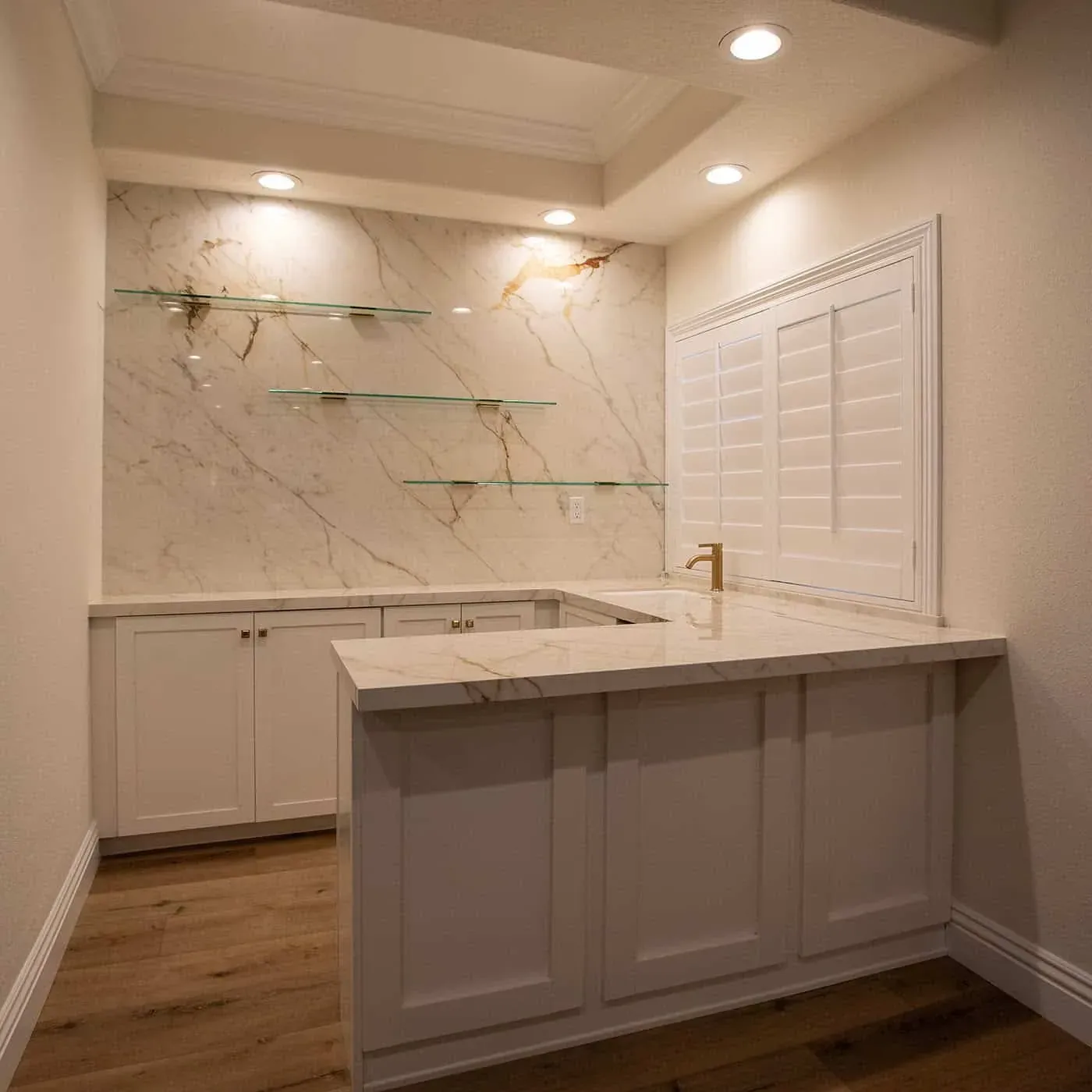 Bar counter with glass shelving set against book-matched marble