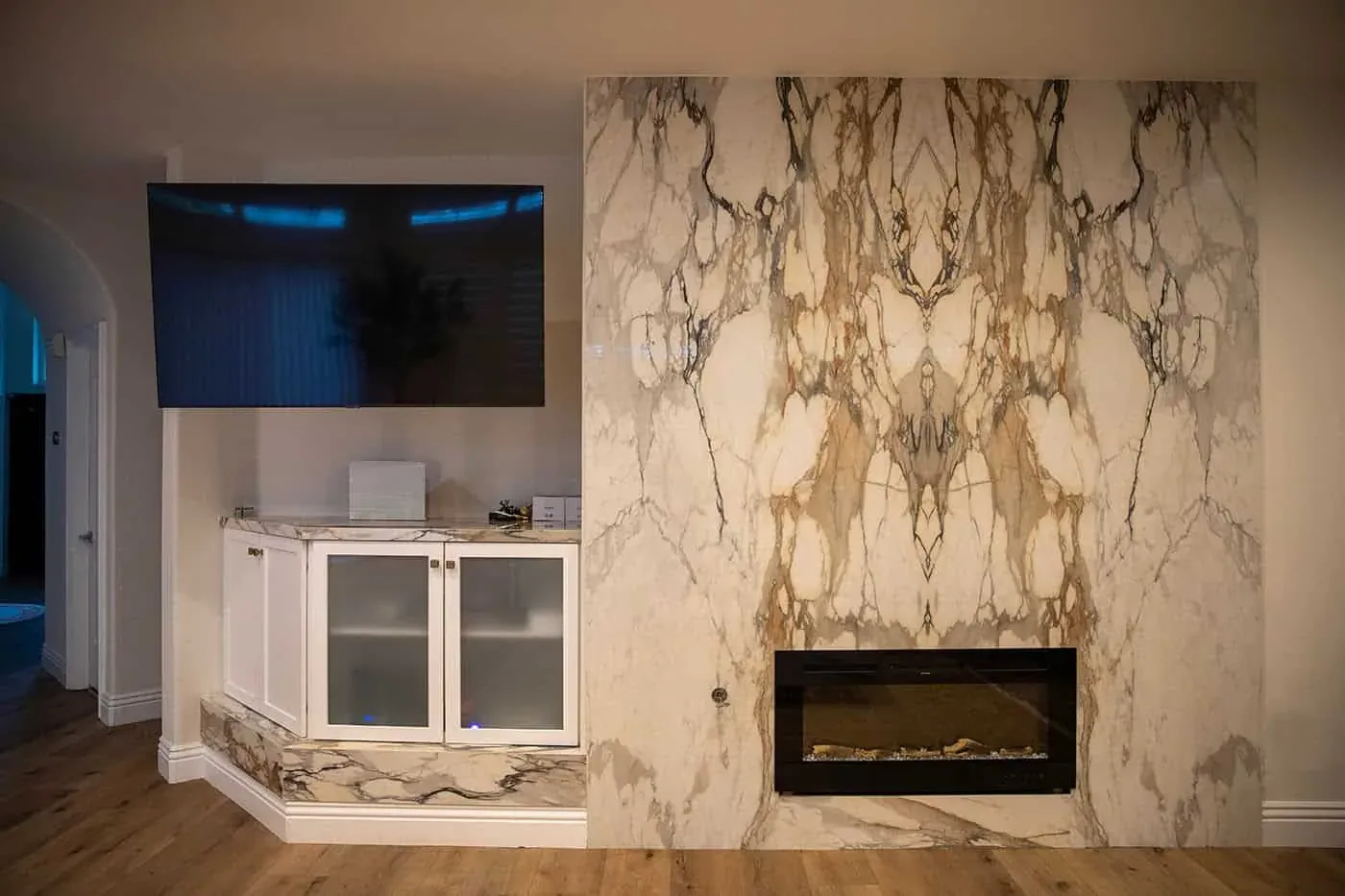 Book-matched marble fireplace wall with a linear fire and wall-mounted television