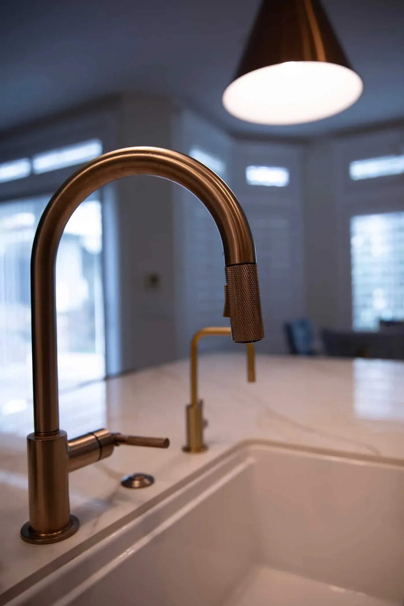 Brass pull-down kitchen tap over a stone worktop