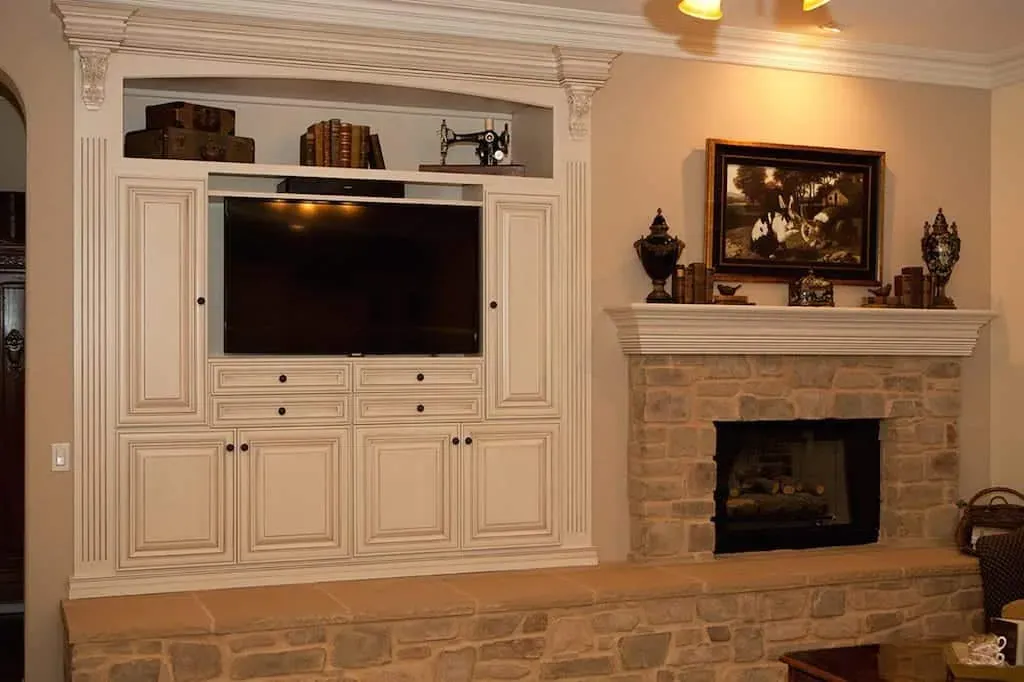 Built-in media wall with a stone fireplace and cream cabinetry