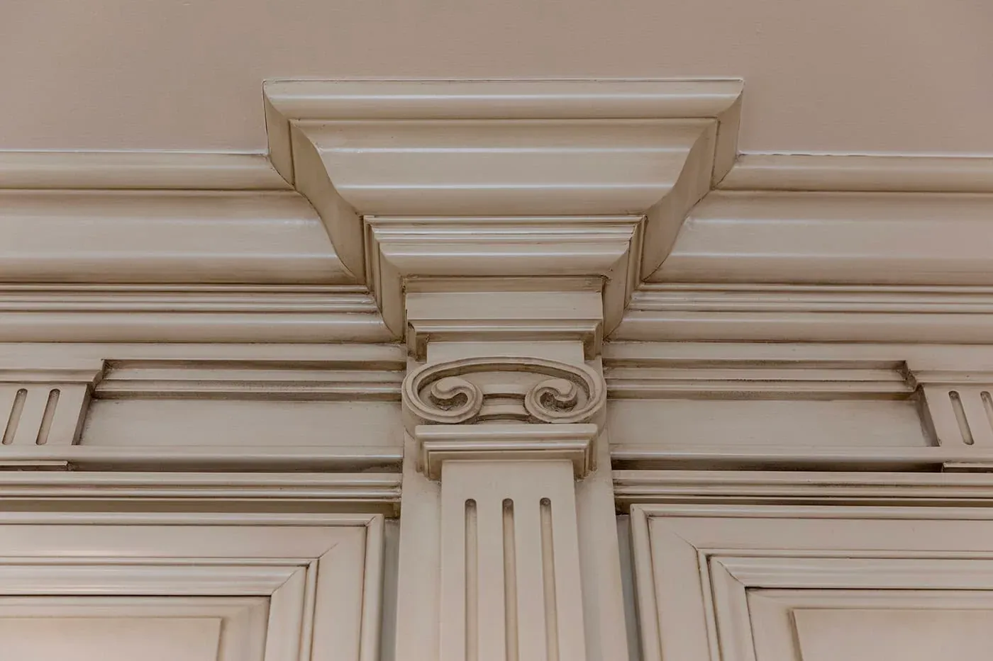 Carved capital and fluted pilaster detail on cream cabinetry