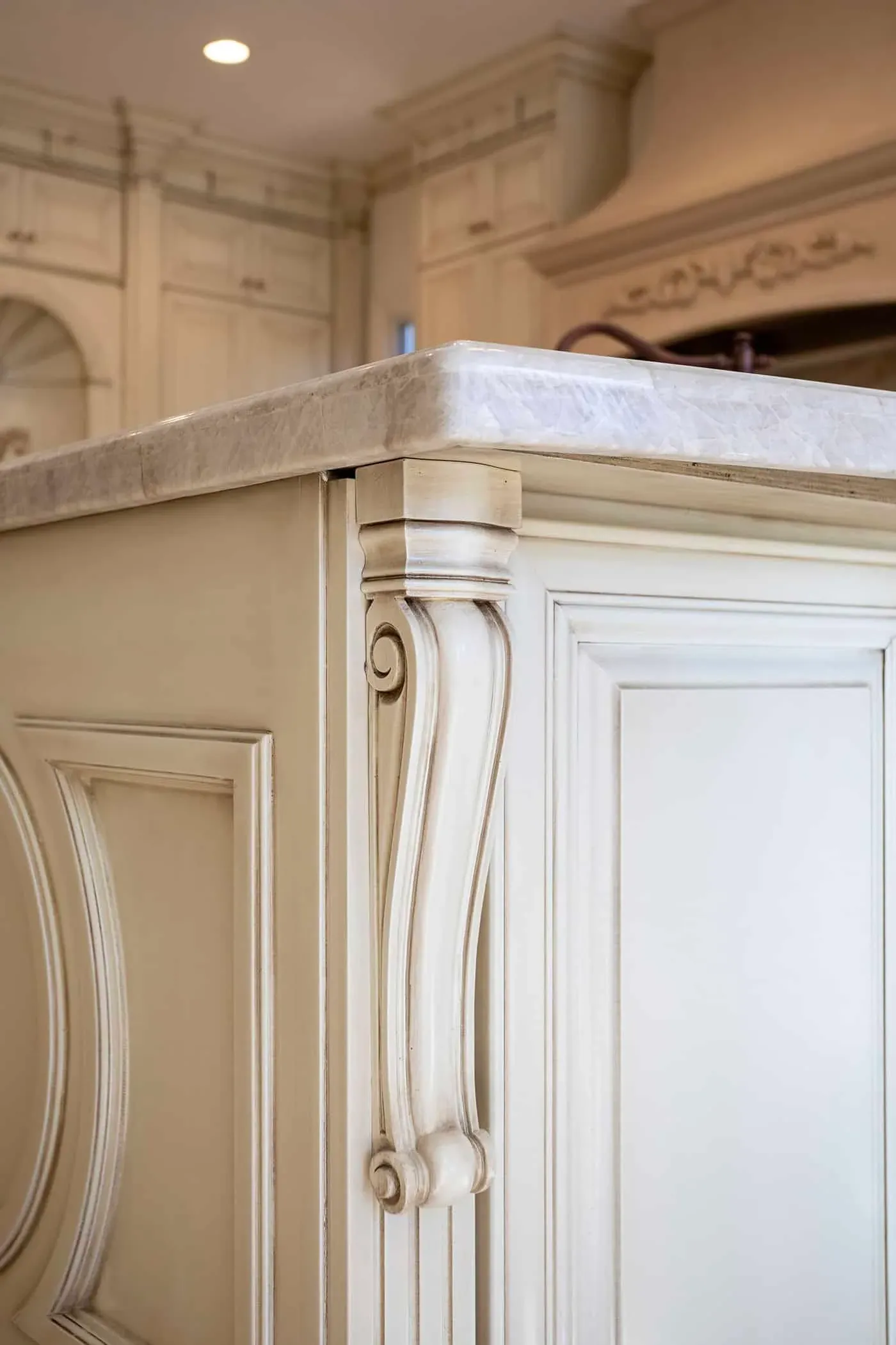 Carved corbel detail on a cream island end panel beneath a stone top