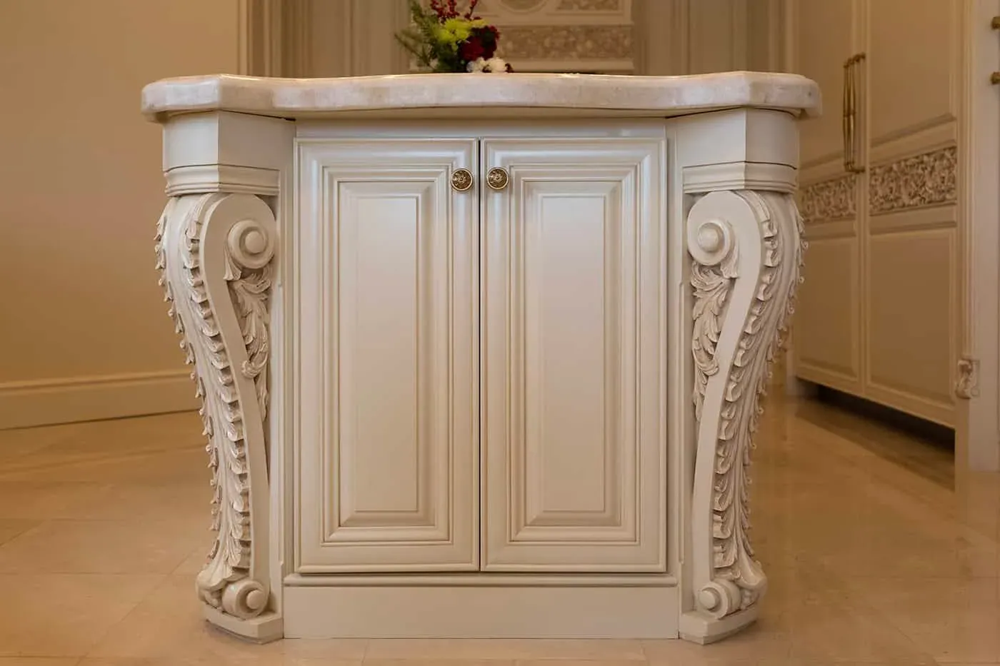 Carved cream island with scrolled corbels and a marble top