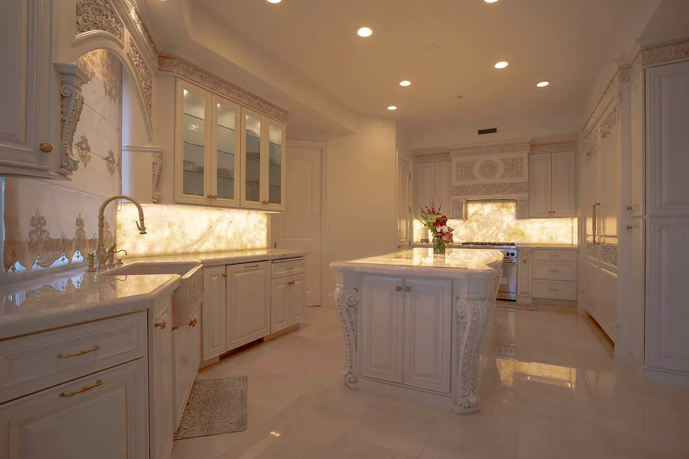 Carved cream kitchen with a backlit onyx backsplash and marble island