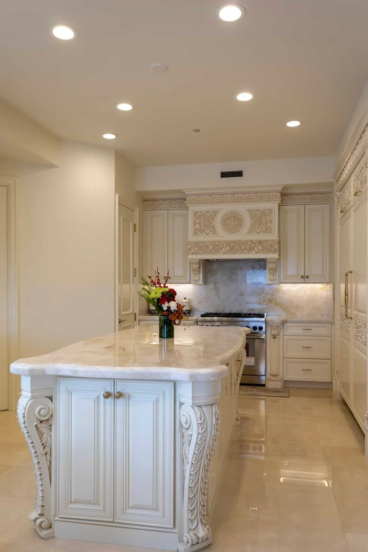 Carved island end with a marble top beside a stainless range