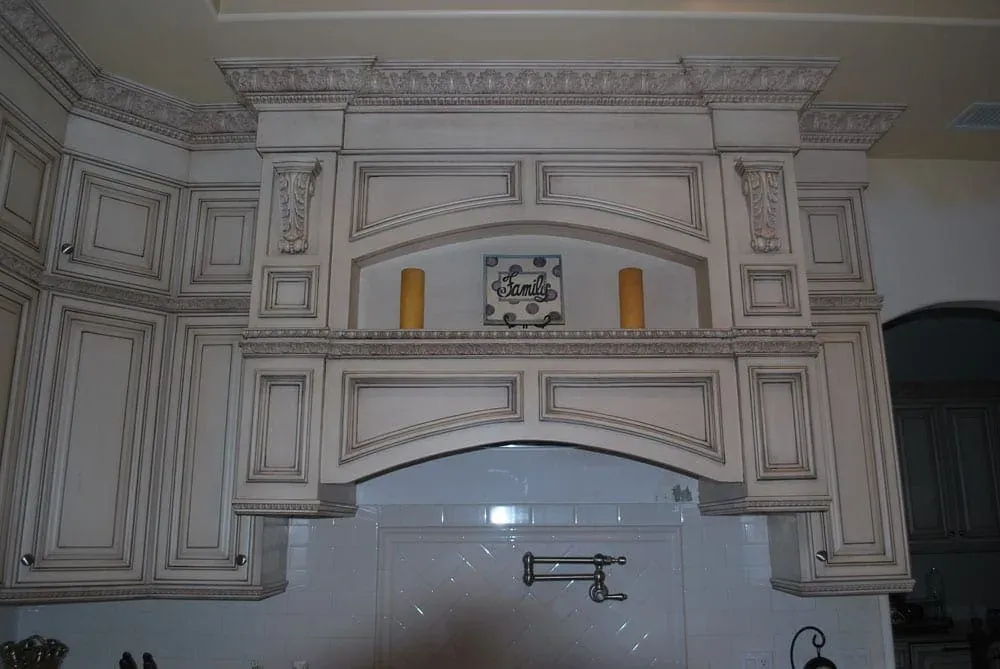 Carved range hood surround with a tiled niche above the cooktop