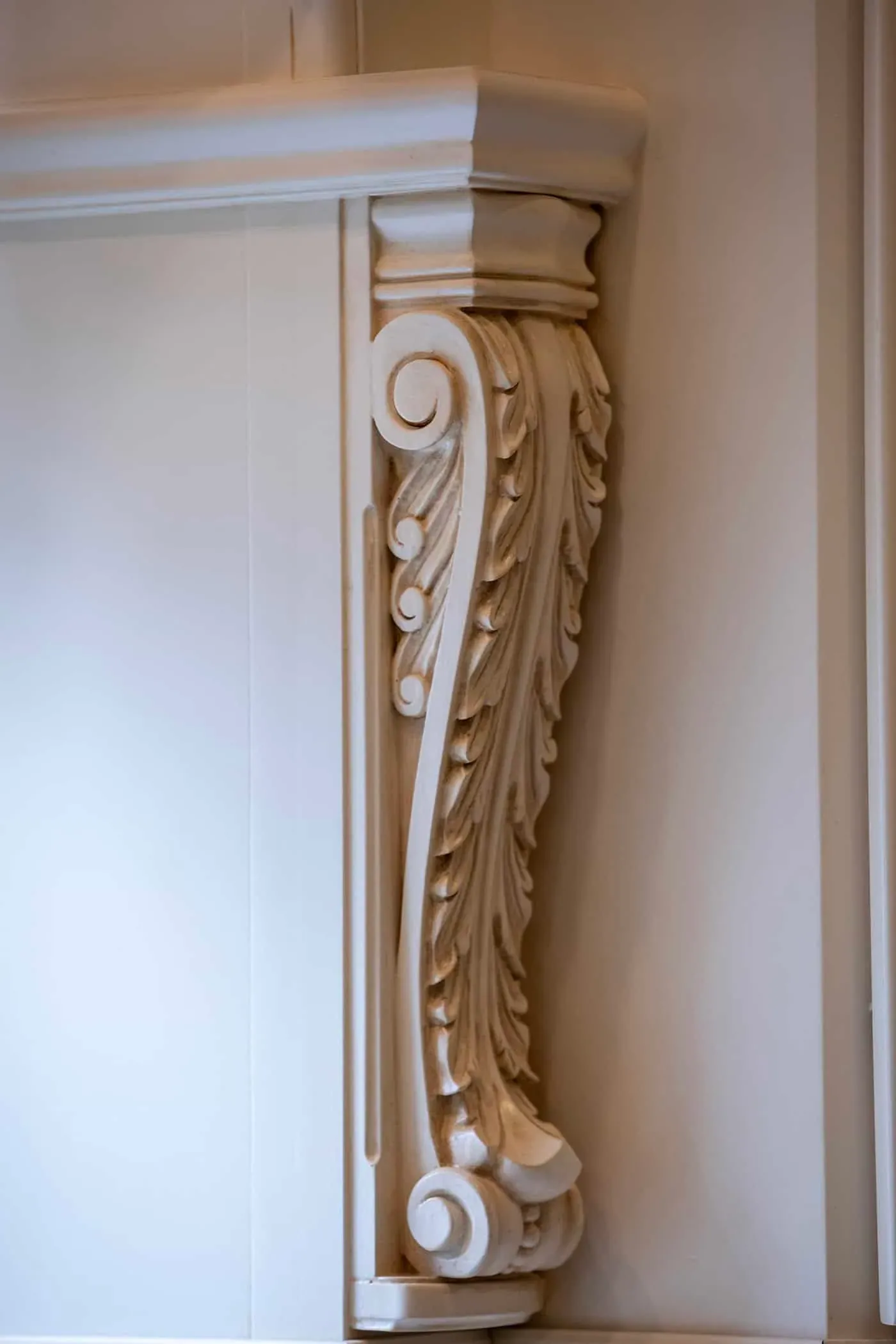 Carved scroll and leaf detail on a cream cabinet stile