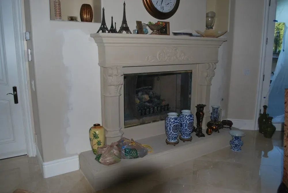 Carved stone fireplace with a large mirror and a decorated mantel