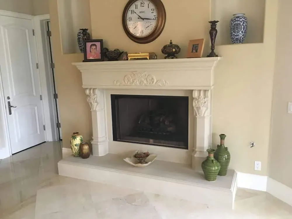 Carved stone mantel with framed photographs and candlesticks