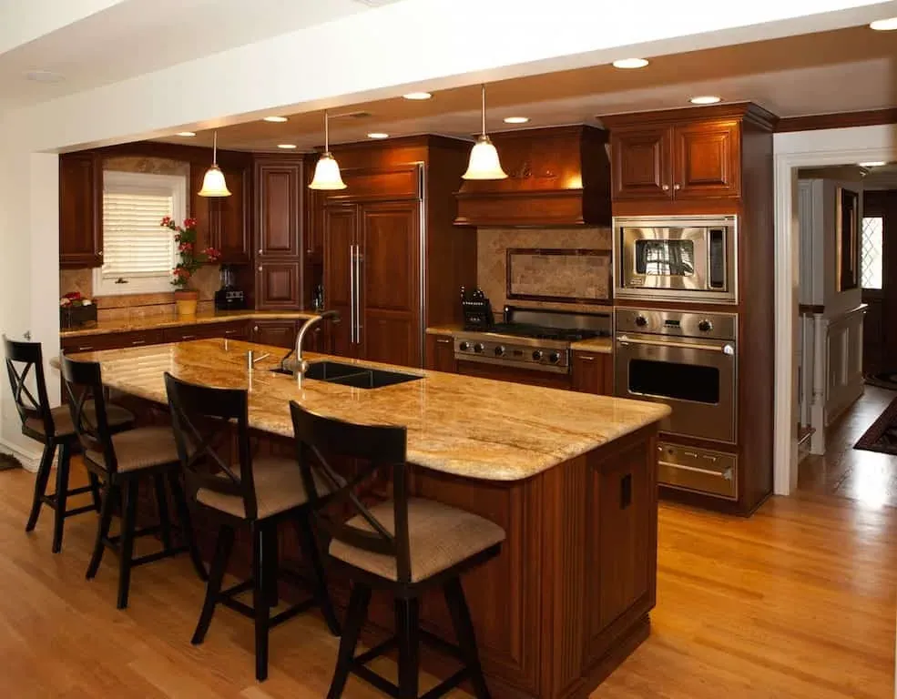 Cherry kitchen with a granite island, bar stools and pendant lights