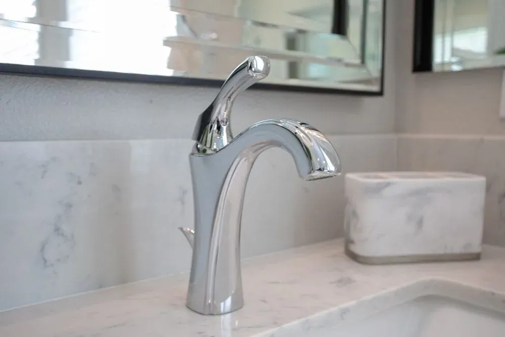 Chrome basin tap on a marble vanity top beneath a mirror
