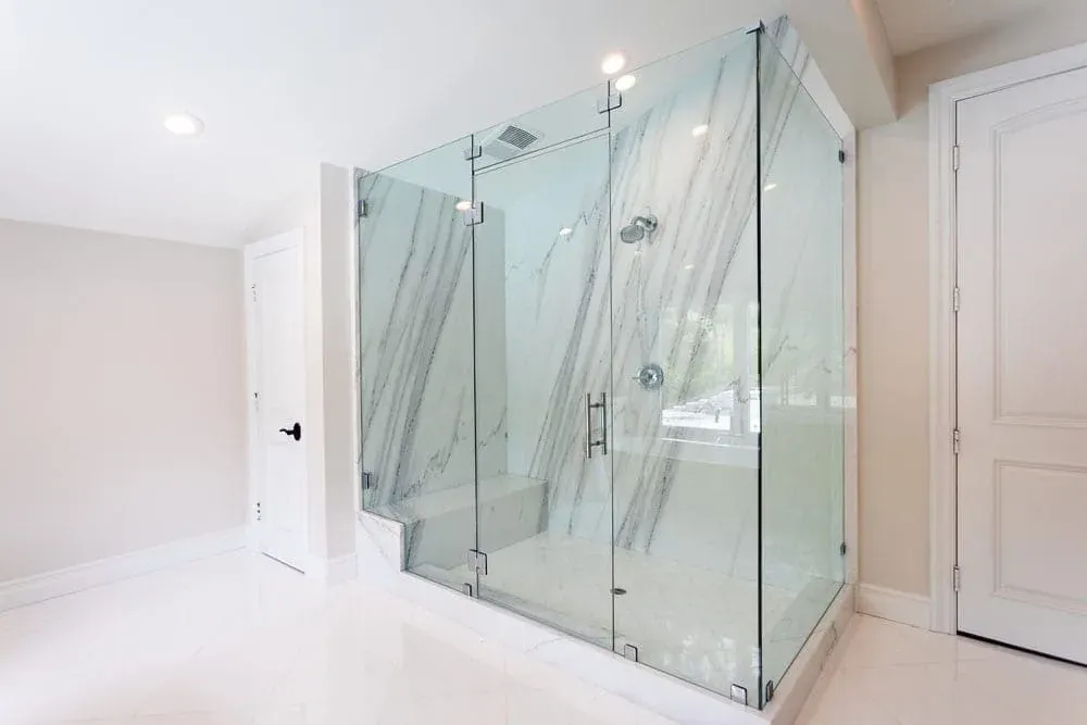 Corner glass shower enclosure with marble slab walls