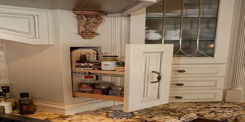 Cream cabinetry with a carved corbel and an open pull-out pantry beside granite counters