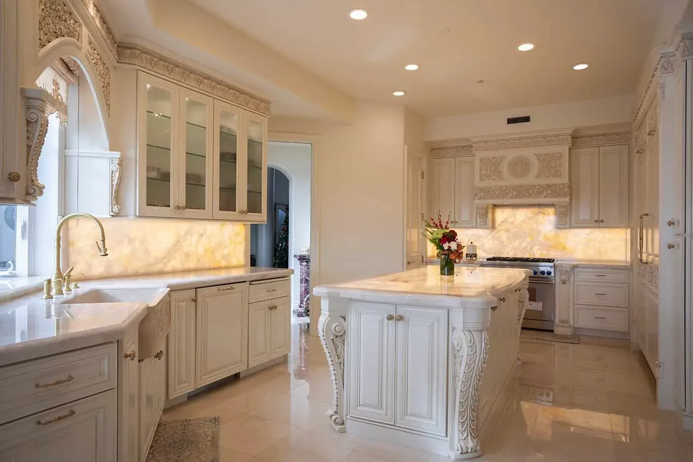 Cream carved kitchen with a backlit onyx island and glass-front cabinets