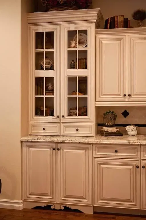 Cream glass-front cabinetry with granite counters and display shelving