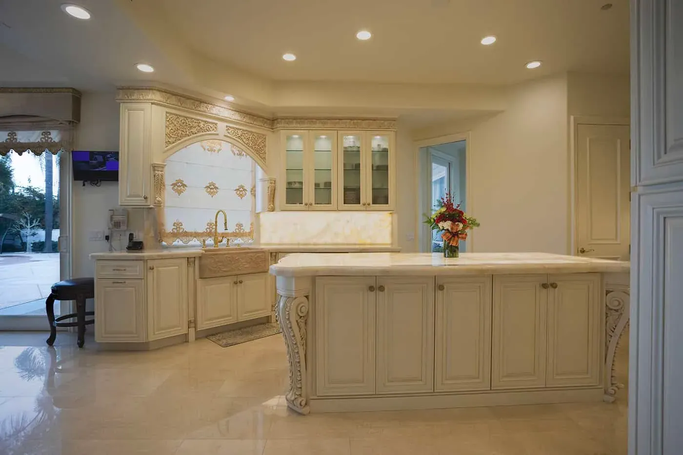 Cream kitchen with a carved island, farmhouse sink and glass cabinets