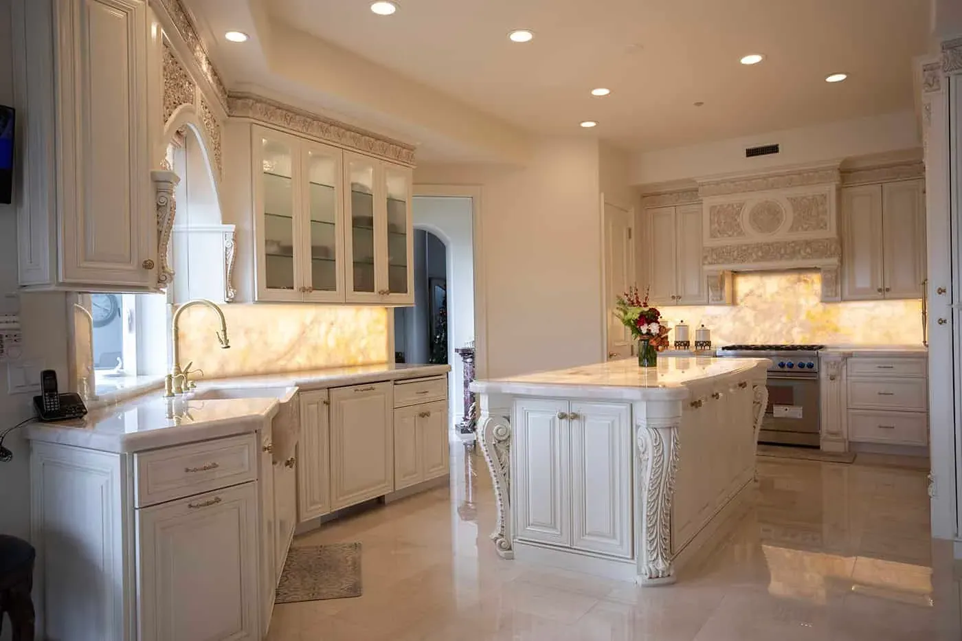 Cream kitchen with a carved island, glass cabinets and an onyx counter
