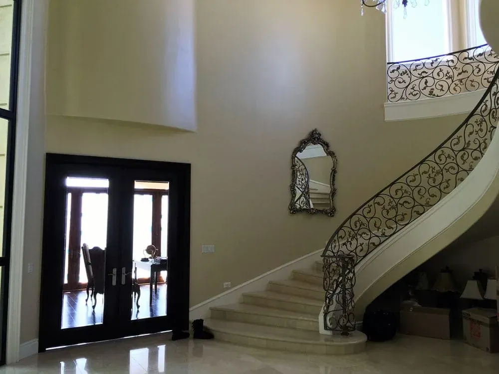 Curved staircase and entry hall seen from the dark double front doors