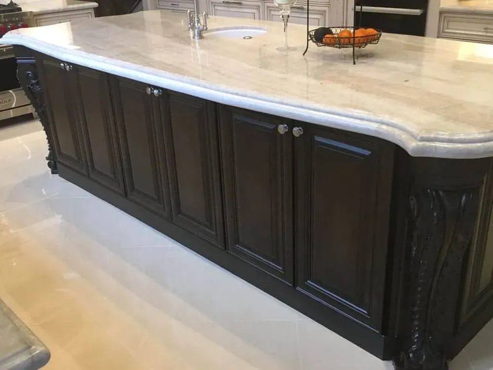 Dark carved island with a thick stone top and an ogee edge