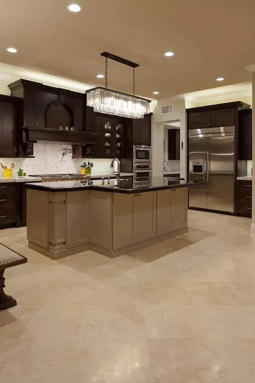 Dark kitchen with a stainless refrigerator, island and linear chandelier