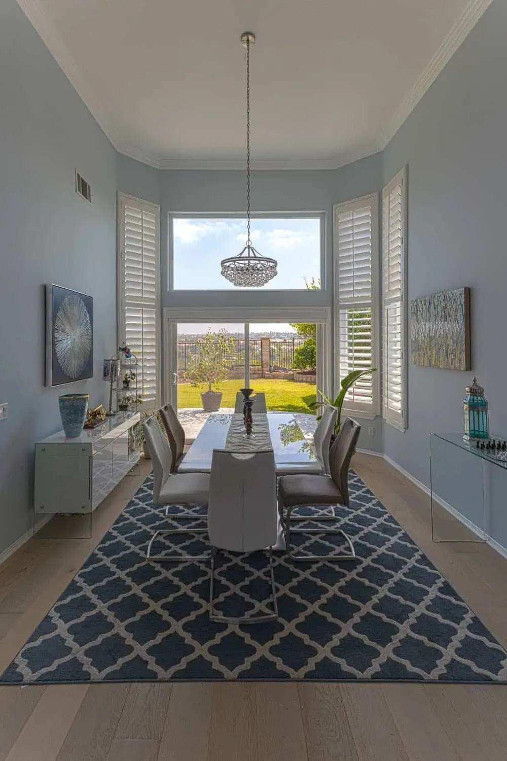 Dining area with a pendant light, shuttered windows and a patterned rug