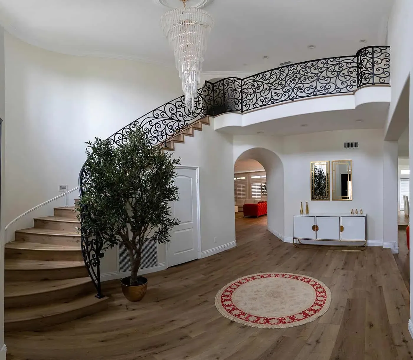 Entry hall with a curved staircase, chandelier and arched opening