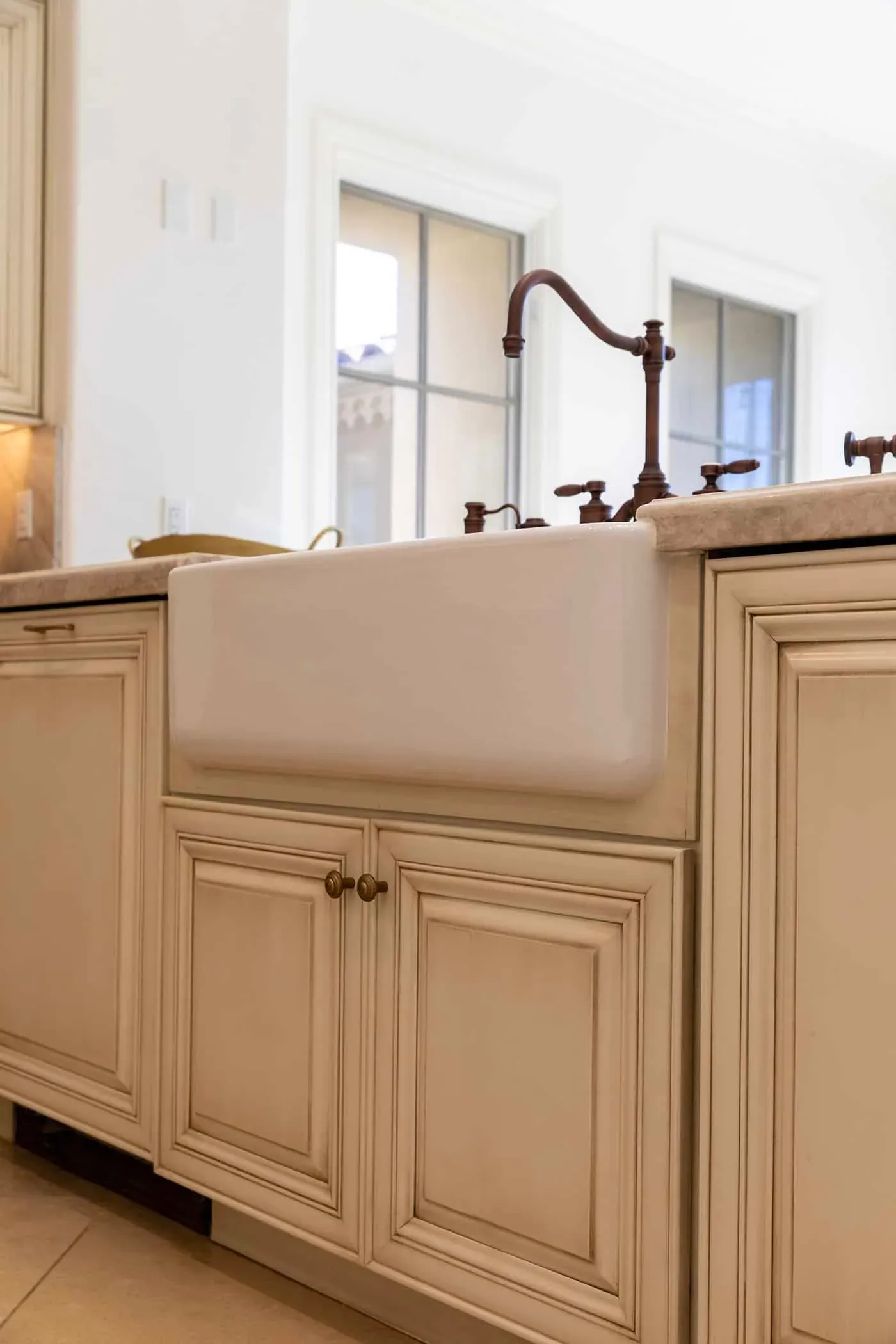 Farmhouse apron sink with a bronze bridge tap in cream cabinetry