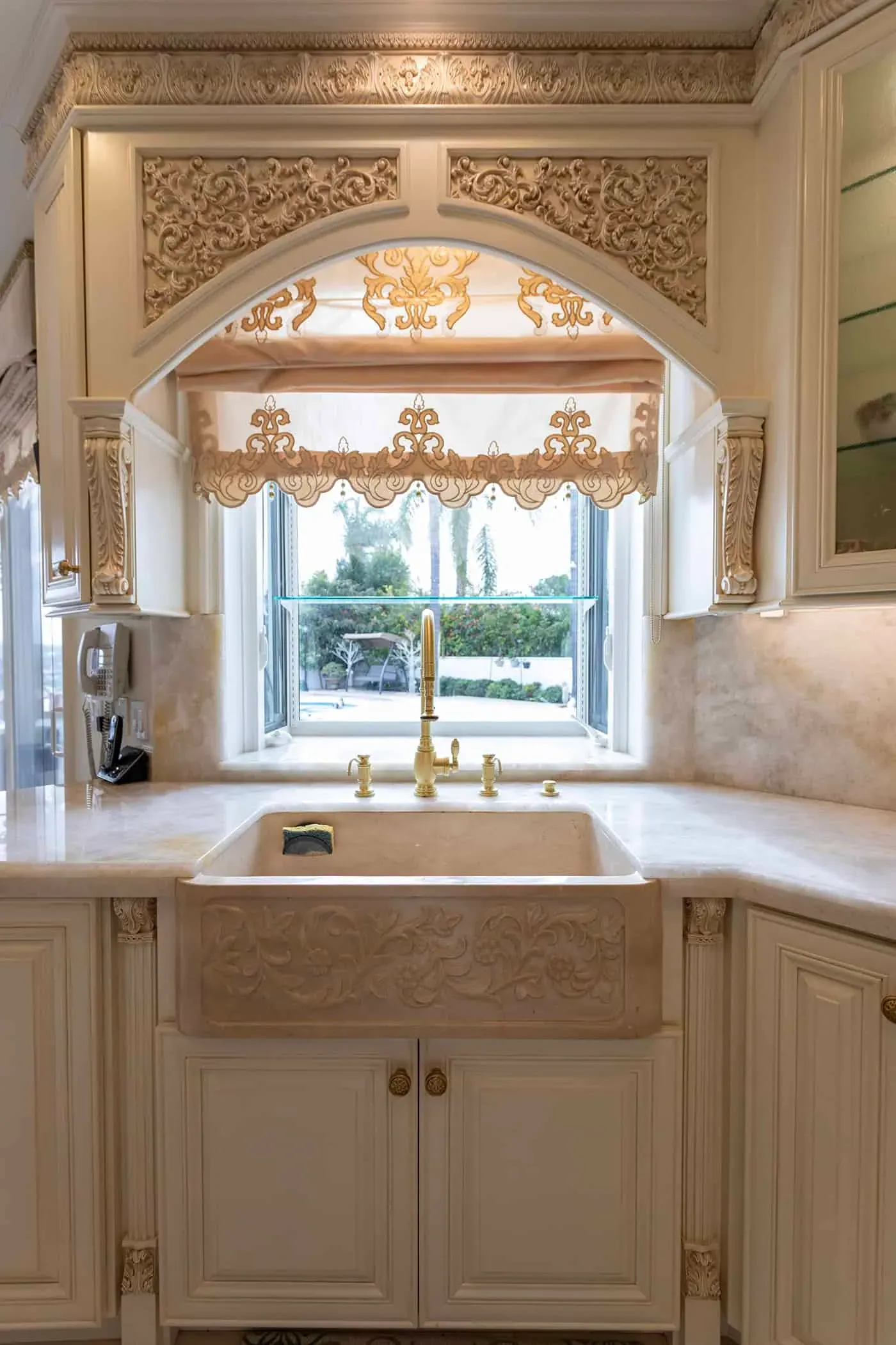 Farmhouse sink beneath an arched window with a brass tap