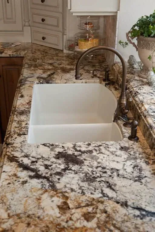 Farmhouse sink with a bronze tap in a speckled granite worktop