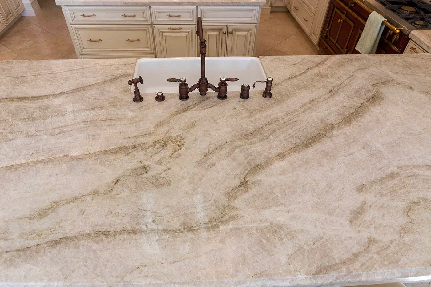 Farmhouse sink and bronze tap on a veined quartzite worktop