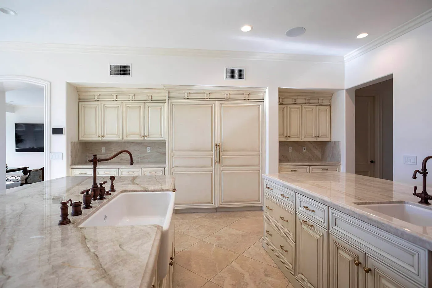 Farmhouse sink on a stone counter with a bronze bridge tap and panelled refrigerator