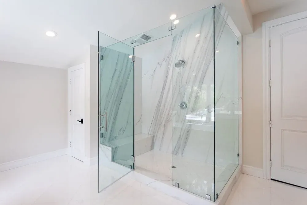 Frameless glass shower enclosure against marble slab walls