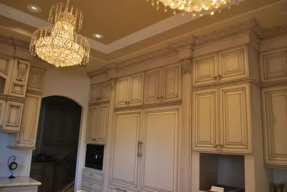 Glazed cabinetry beside an arched opening under a crystal chandelier