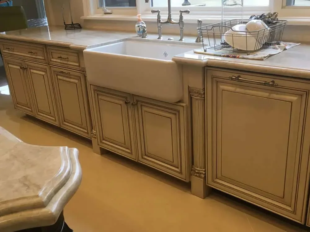 Glazed cabinetry with a farmhouse apron sink and a bridge tap on a stone worktop