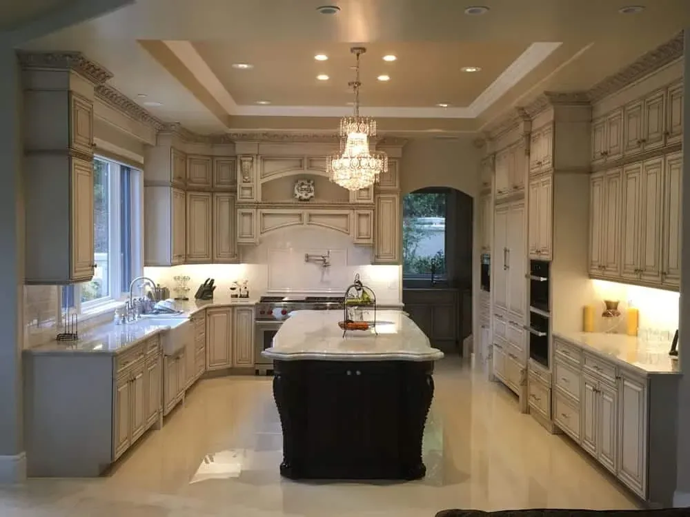 Glazed cream kitchen with a dark island and crystal chandeliers
