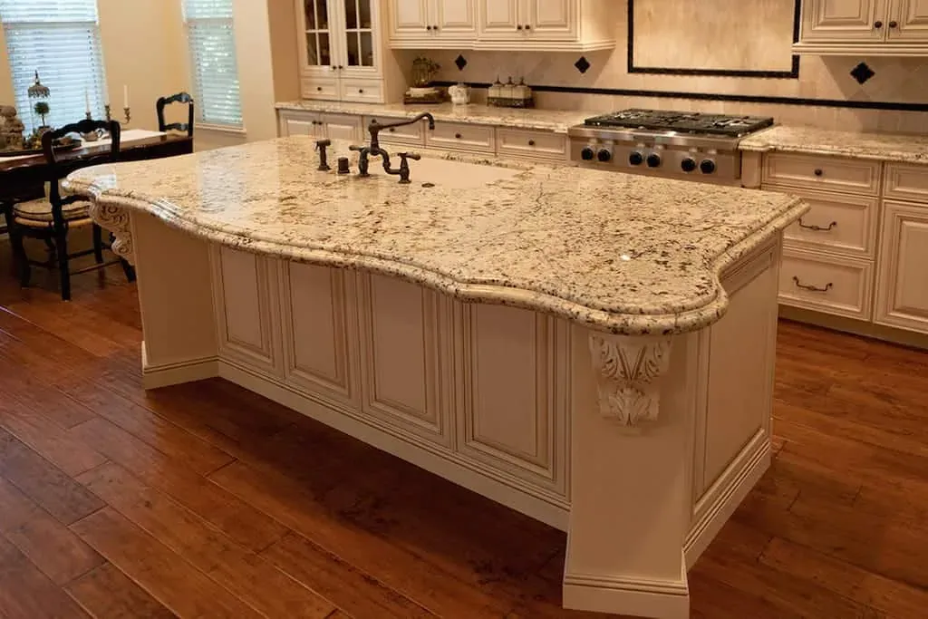 Granite island with carved corbels and a bronze tap