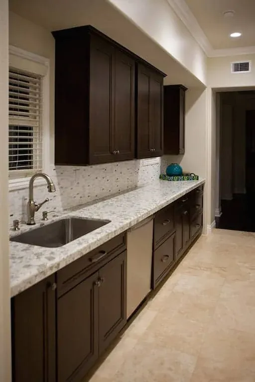 Dark base cabinets with a granite worktop and a mosaic backsplash