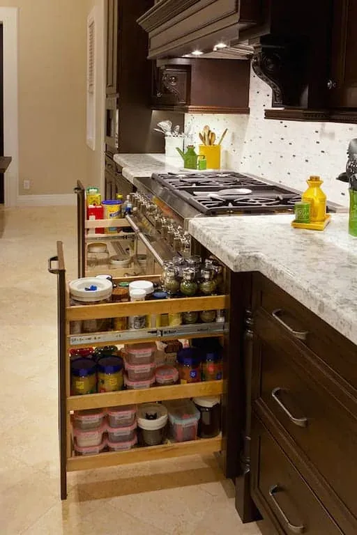 Dark cabinetry with a pull-out spice rack beside a cooktop