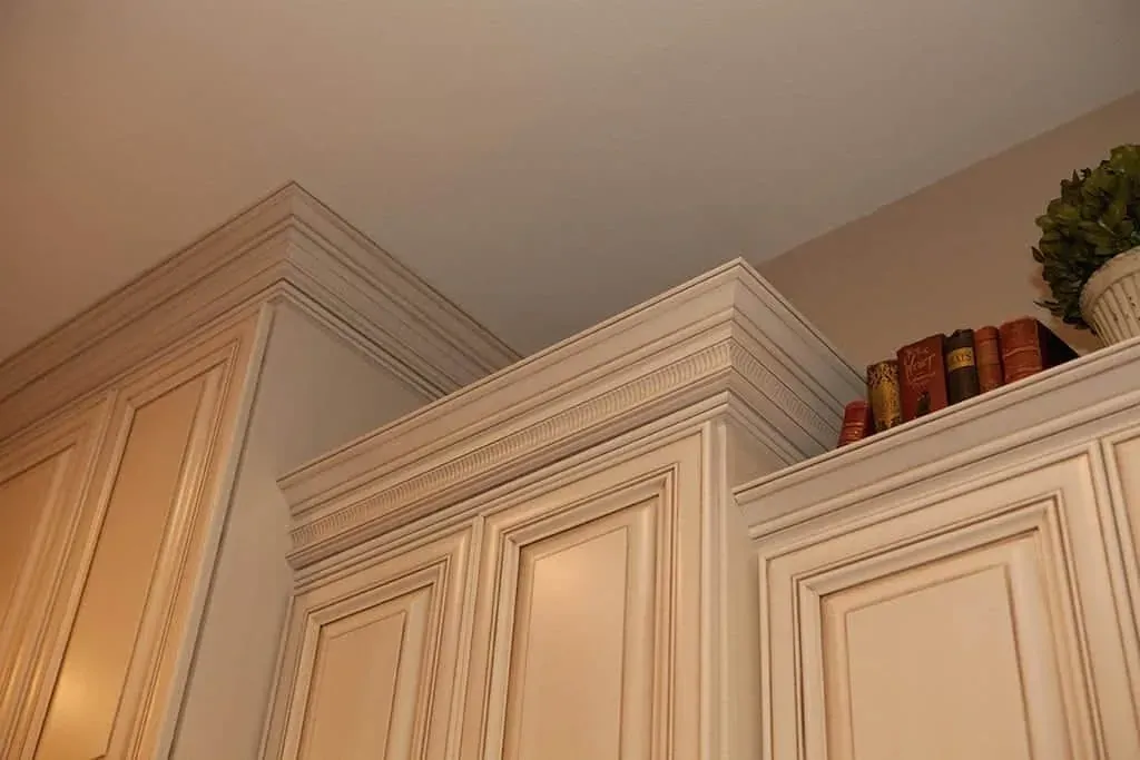 Cream cabinetry with crown moulding against a plain wall