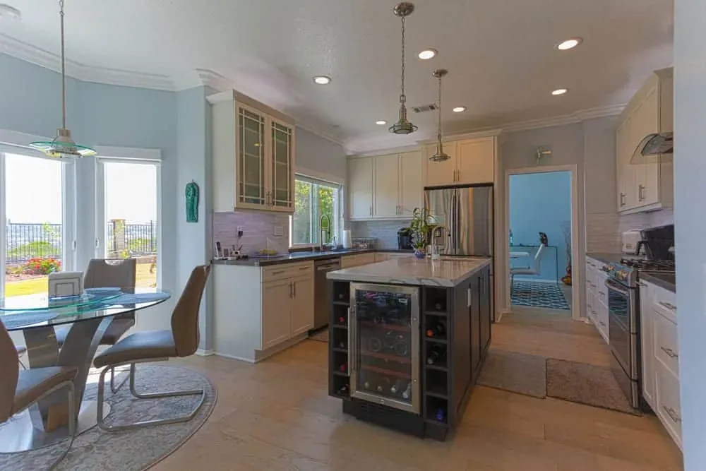 Kitchen with a dark island, wine cooler and dining area beyond