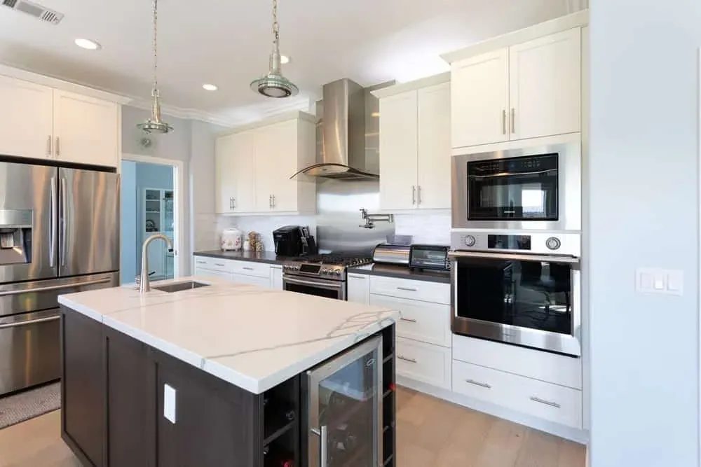 White kitchen with a stainless hood, dark island and wine cooler