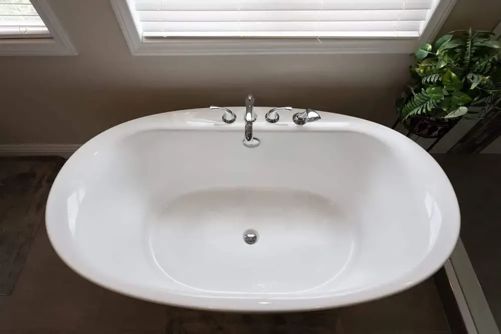 Oval drop-in tub set into a tiled surround with planting