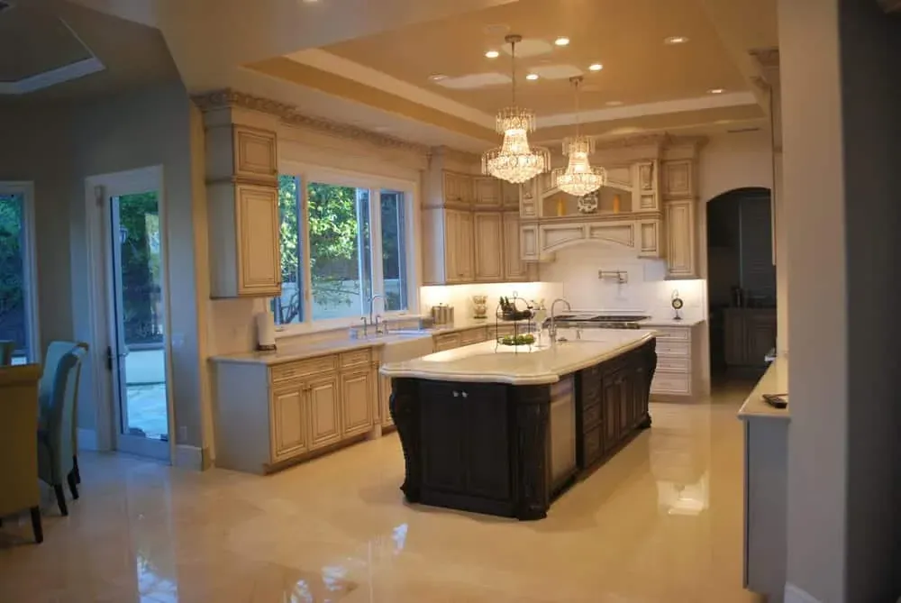 Cream glazed kitchen with a dark island and pendant chandeliers