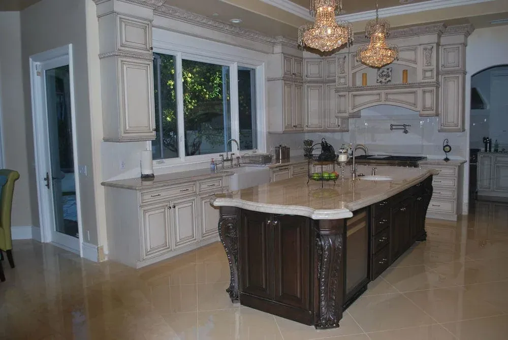 Kitchen with two chandeliers, a dark carved island and a window wall