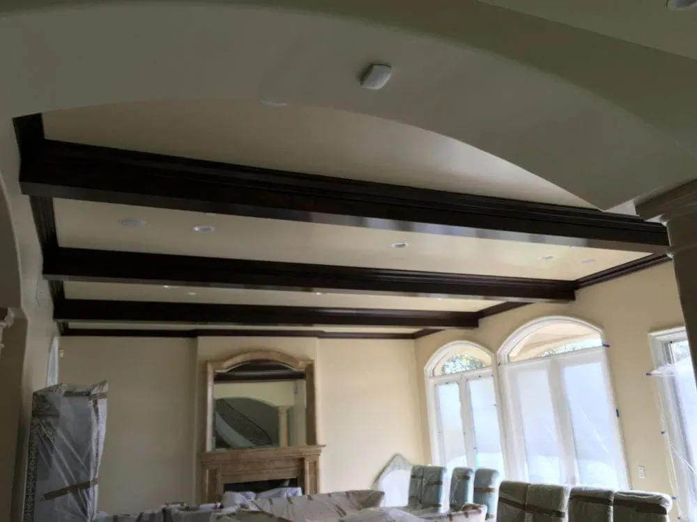 Living room with dark exposed ceiling beams, arched windows and a console mirror