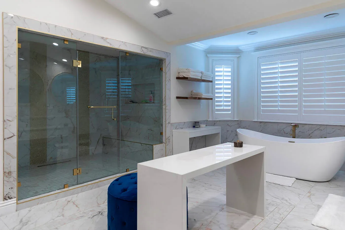 Marble bathroom with a floating vanity, plantation shutters and freestanding tub