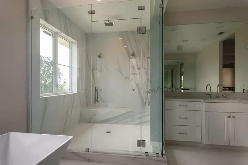 Marble bathroom with a glass shower, vanity and window