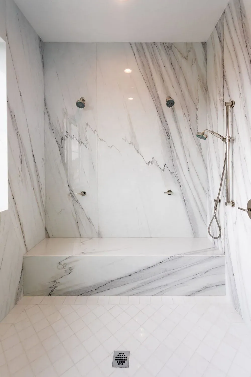 Marble shower with a built-in bench and handheld shower